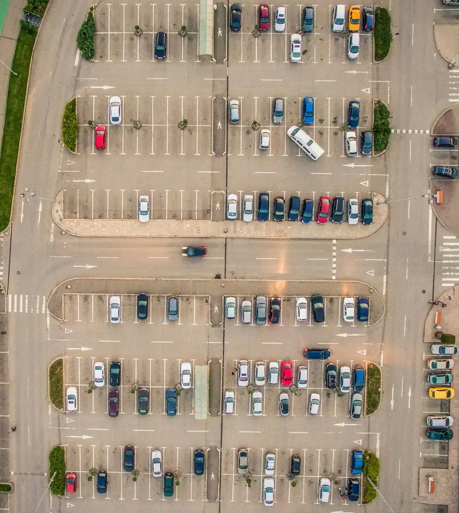 Aerial view of a busy commercial parking lot with marked spaces and drive lanes